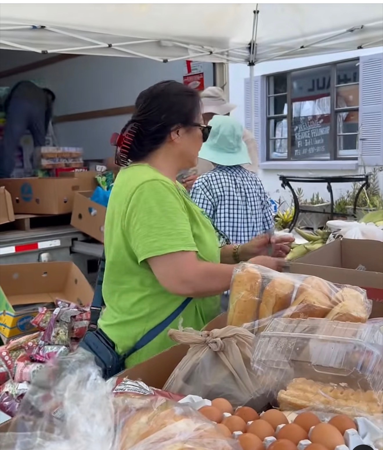 A volunteer in a green shirt arranging loaves of bread beside boxes of eggs